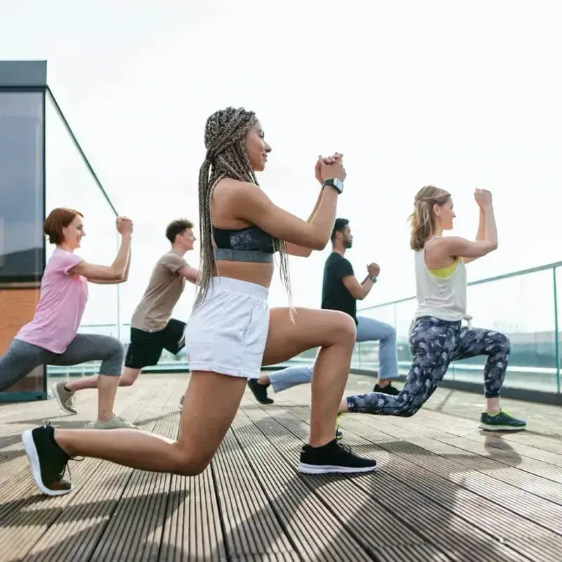 Group of people of various ages stretching on a rooftop